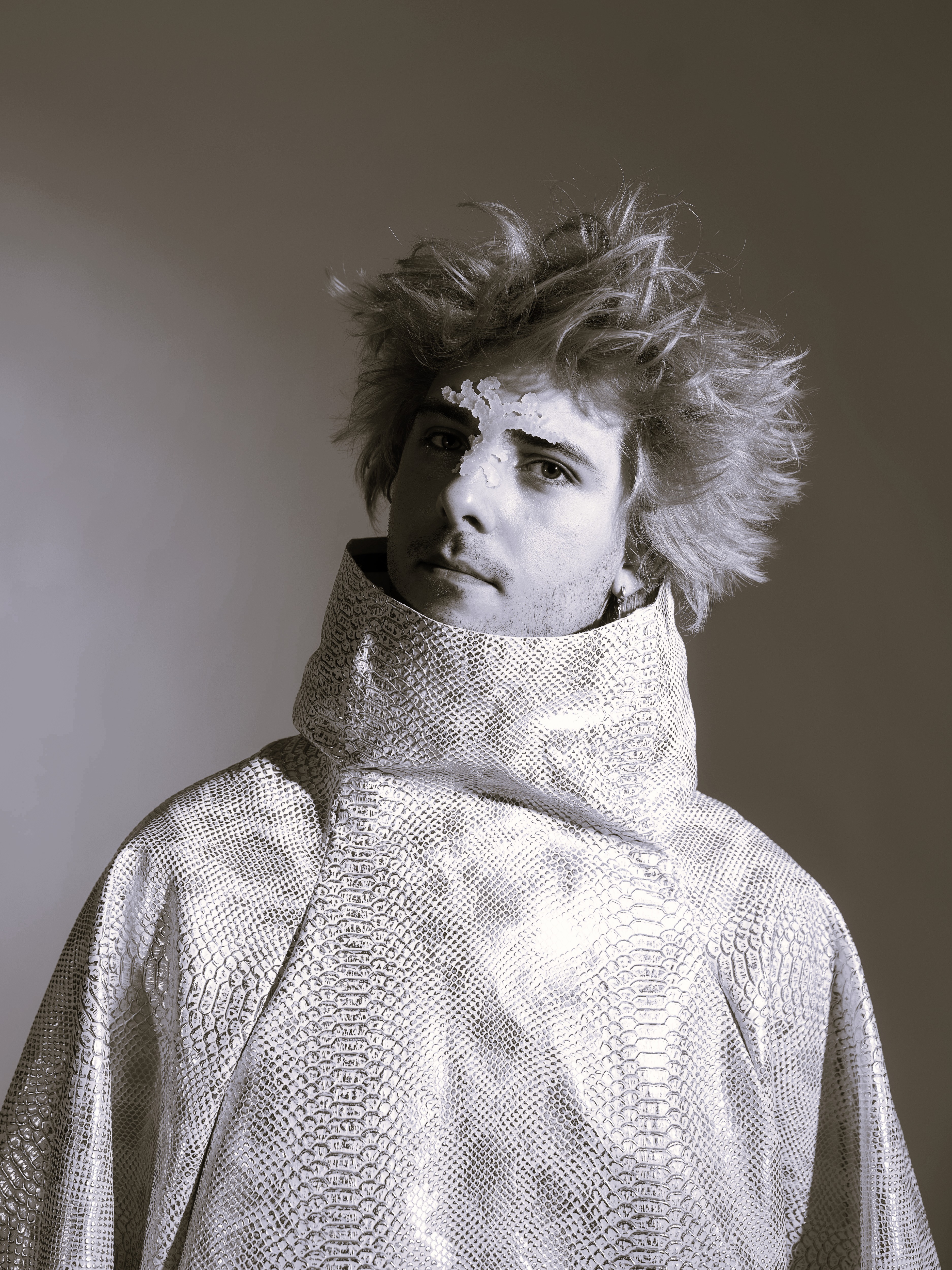 Eine Person mit blauen, abstehenden Haaren und einem extravaganten Pullover